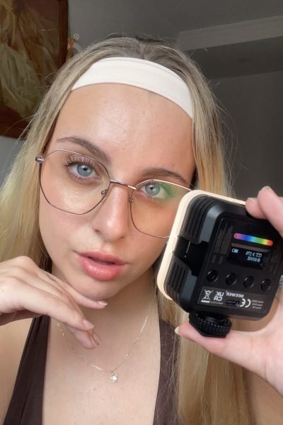 Mujer rubia con gafas sujetando productos de belleza de la marca Beverll frente a la cámara.