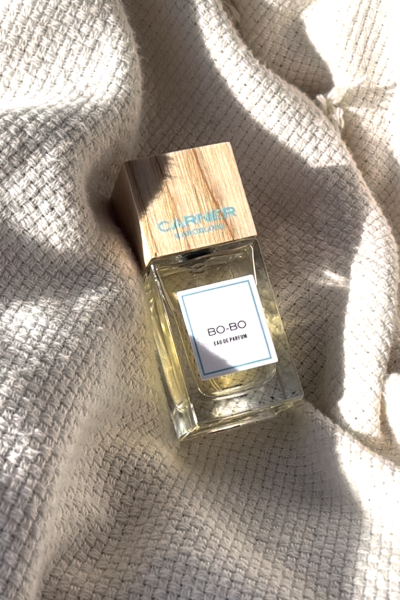 Frasco de perfume Carner Barcelona "BO-BO" sobre una tela beige suave.