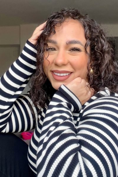 Handymar López sonriendo frente a la cámara con jersey de rayas y cabello rizado para contenido UGC de belleza y lifestyle.