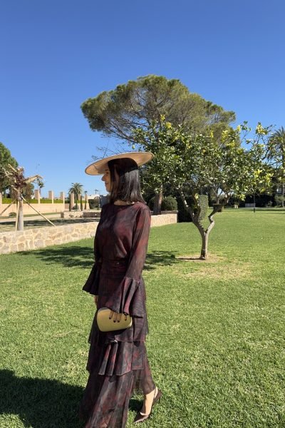 Luna Cabrera, creadora UGC, con vestido largo estampado, sombrero y bolso en un entorno natural y elegante | Agencia Brilla Influencers