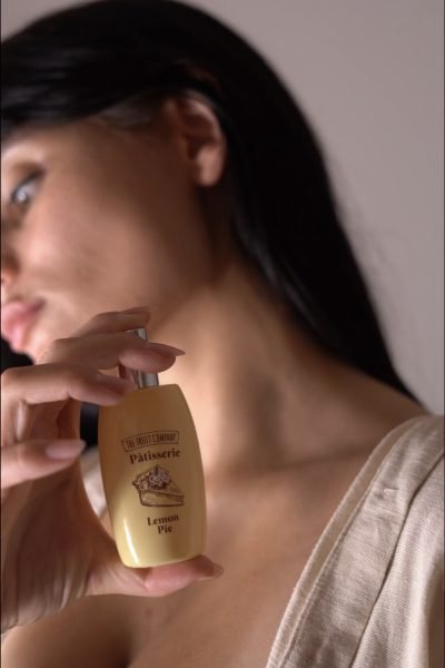 Nerea Torres sosteniendo el perfume "Lemon Pie" de la colección Pâtisserie de The Fruit Company cerca de su cuello.