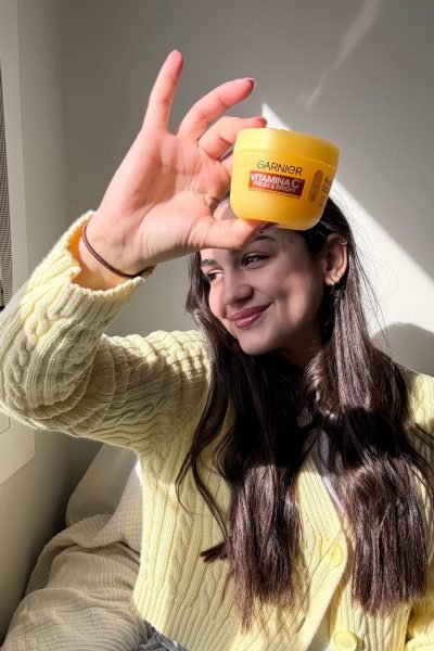María sosteniendo un envase de crema Garnier Vitamina C Fresh & Bright frente a su rostro.