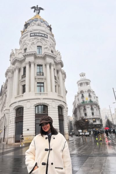 Laura Freyta posando frente al edificio Metrópolis de Madrid con un look invernal, creando contenido UGC de lifestyle, moda y turismo urbano.