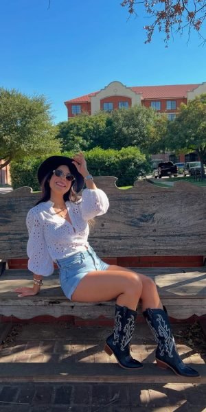 Laura Rojas con sombrero y botas vaqueras, posando al aire libre en un banco de madera. Agencia de marketing digital Brilla Influencers y Comunicación.