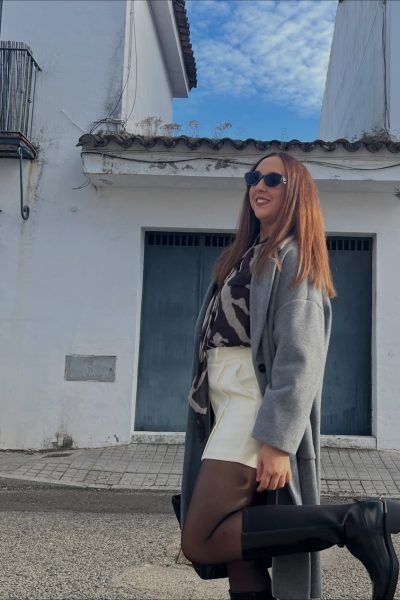 Lola Martín González posando con botas altas y abrigo gris en la calle.