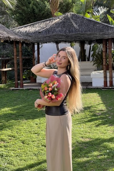 Lucía Cardona posando con un ramo de flores en un entorno tropical.
