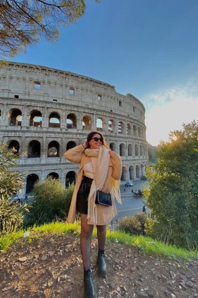 Lucía Pérez García posando frente al Coliseo de Roma con un outfit elegante de invierno y accesorios de moda.