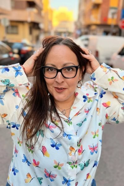 Mari Carmen Poveda posando en la calle con camisa de mariposas - Agencia de marketing digital Brilla influencers y Comunicación
