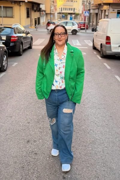 Mari Carmen Poveda caminando por la calle con chaqueta verde - Agencia de marketing digital Brilla influencers y Comunicación