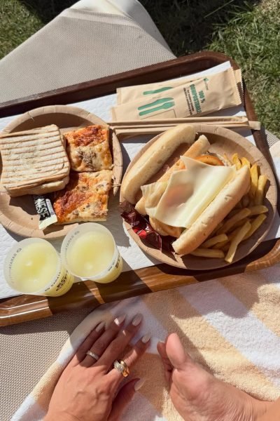 Comida compartida al aire libre con bocadillos, pizza y bebidas en una jornada de lifestyle y gastronomía.