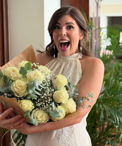 María Anaya, creadora UGC, sonríe felizmente mientras sostiene un ramo de rosas blancas, mostrando su estilo cálido y natural.