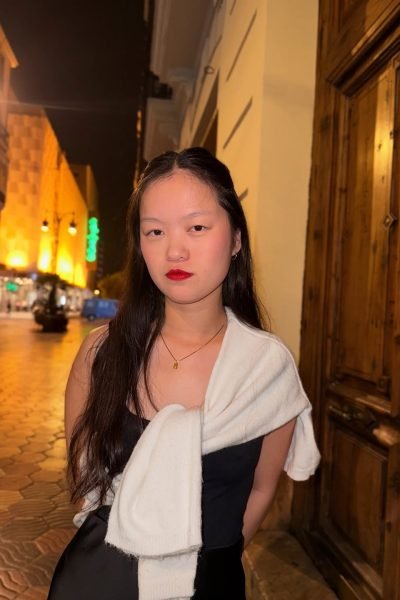 Agencia de marketing digital Brilla Influencers y Comunicación, María Benids con vestido negro y suéter blanco, frente a fondo urbano nocturno.