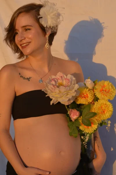 mujer embarazada sosteniendo flores en sesión lifestyle con luz cálida natural