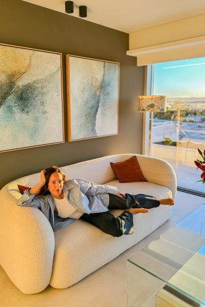 María Huidobro posando en un salón moderno sobre un sofá de diseño, con luz natural y una estética elegante y sofisticada.