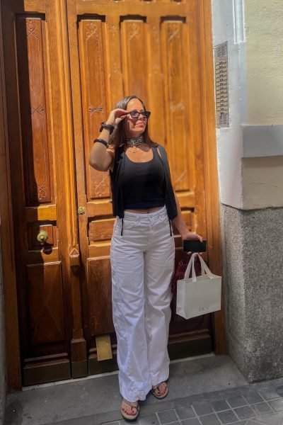 María Huidobro posando frente a una puerta de madera con un outfit elegante y accesorios de moda en un entorno urbano.