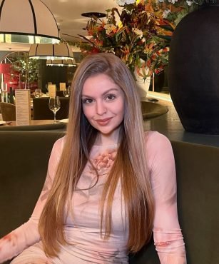 María Navarro posando en un restaurante, con un vestido floral de tonos suaves. UGC elegante y sofisticado.