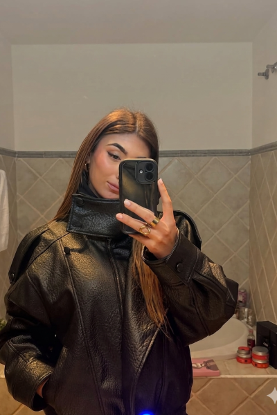 Mireya Sánchez tomando un selfie frente al espejo con chaqueta de cuero negra y pelo suelto.