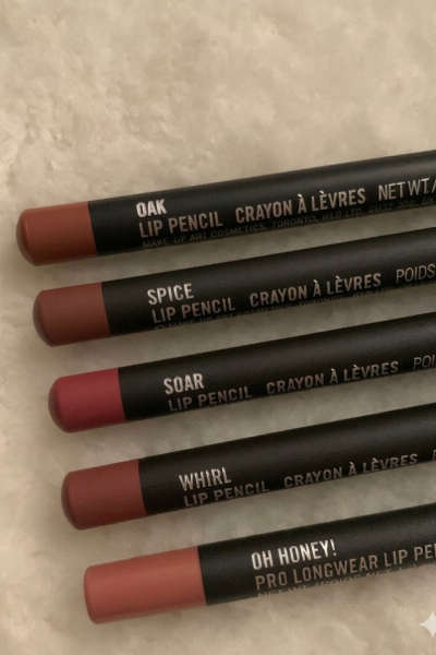 Cinco lápices de labios alineados sobre una superficie mostrando diferentes tonos de maquillaje.