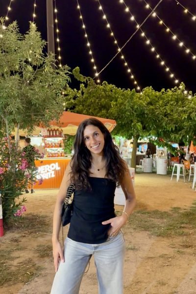 Paula Alsina luciendo un estilo elegante con una blusa de seda mientras disfruta de una tarde al aire libre.