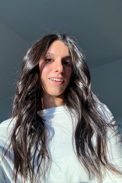 Paula Alsina relajada, con un atuendo sencillo mientras disfruta de un entorno soleado y fresco, transmitiendo calma y confort.