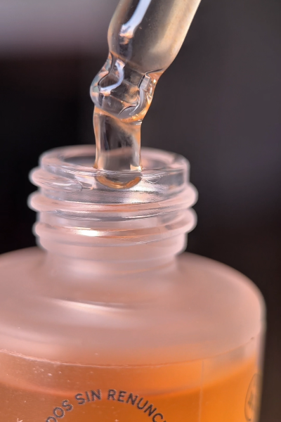 Primer plano de un sérum siendo vertido, con detalles suaves del producto.