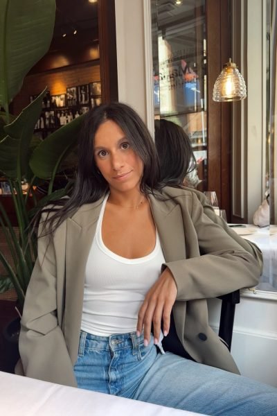 Paula Alsina en restaurante, chaqueta beige y jeans, estilo casual chic.
