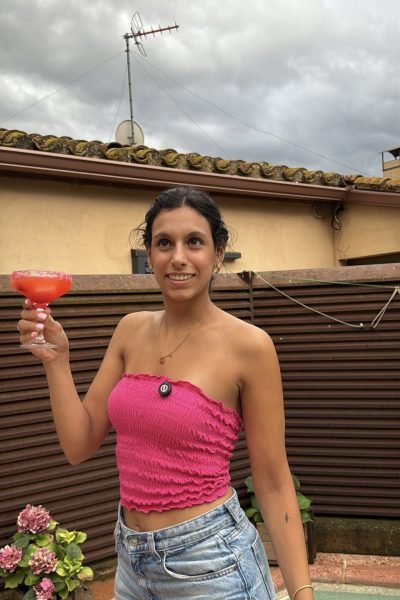 Paula Alsina muestra una imagen fresca mientras sostiene un cóctel en un ambiente festivo y relajado al aire libre.