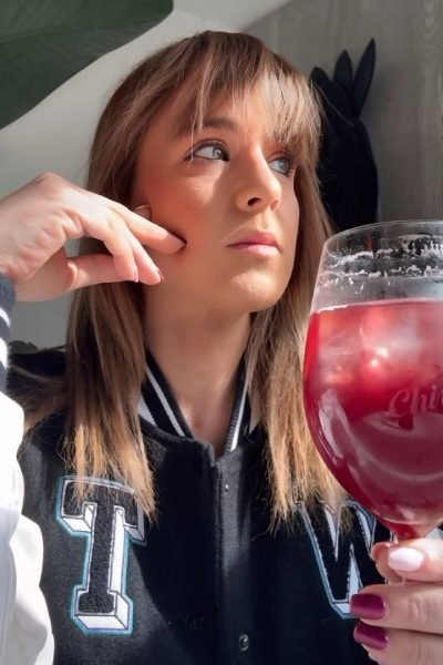 Rosa Alcázar Morales de Valencia tomando un cóctel rojo en vaso grande, mostrando estilo casual y moderno