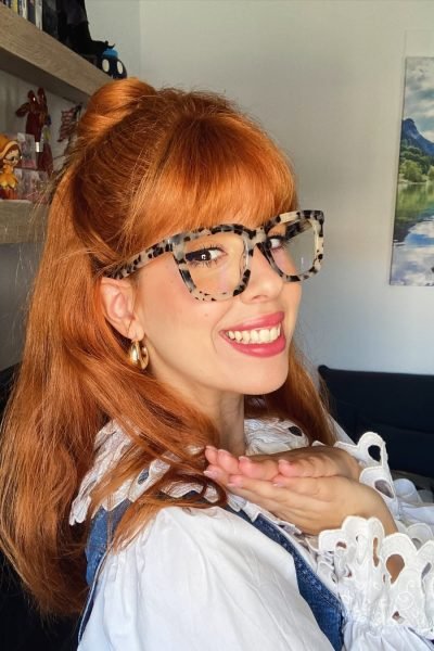 Sara Ramajo sonriendo mientras muestra unas gafas de diseño en una campaña de moda y lifestyle.
