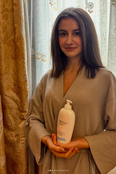 Chica sosteniendo producto de skincare con bata y estética wellness