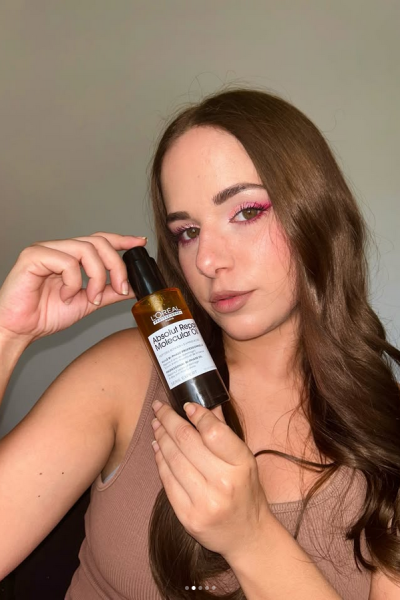 Natalia sosteniendo aceite capilar L’Oréal Absolut Repair Molecular Oil frente a cámara, con cabello cuidado y peinado natural.