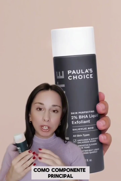 Mujer mostrando un exfoliante Paula's Choice frente a la cámara, explicando sus beneficios de cuidado facial.