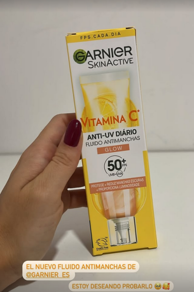 Mano sosteniendo el fluido antimanchas con Vitamina C de Garnier SkinActive, con protección solar 50+.