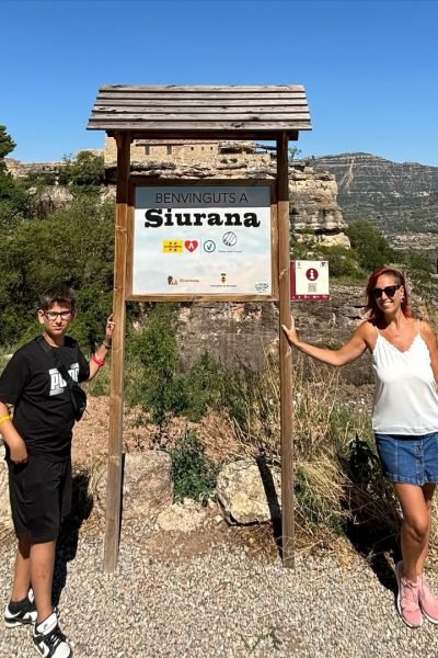 Susanna Ayala Garcia posando junto a una señal de bienvenida en un pueblo.
