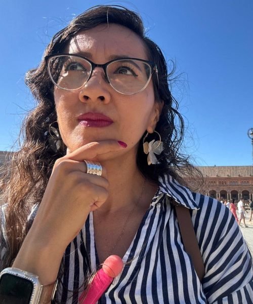 María del Carmen Ramírez, creadora UGC, pensativa frente a la Plaza de España en Sevilla, mostrando su estilo único en contenido de viajes y lifestyle.