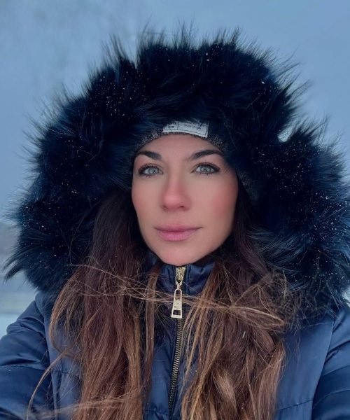Agencia de marketing digital Brilla Influencers y Comunicación, mujer con abrigo azul y capucha de peluche en un paisaje nevado.