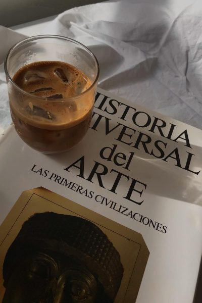 Café frío sobre un libro de historia del arte en una escena lifestyle creada por Ana Yao Gómez López – Agencia Brilla.