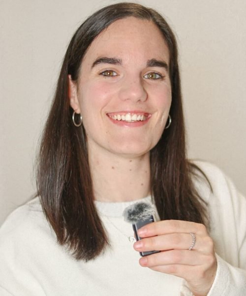 Ane Ajuria mostrando un micrófono mientras sonríe, en un fondo neutro. Agencia de marketing digital Brilla influencers y Comunicación