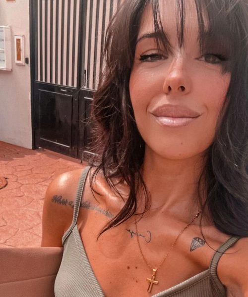 Agencia de marketing digital Brilla Influencers y Comunicación, retrato de mujer con top verde y collar, frente a una puerta y pared