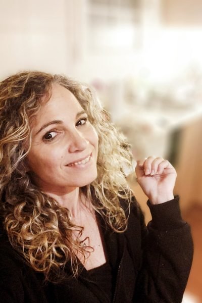 Vanesa Casanovas sonriendo en un retrato lifestyle con cabello rizado y estilo casual, transmitiendo cercanía, confianza y naturalidad.
