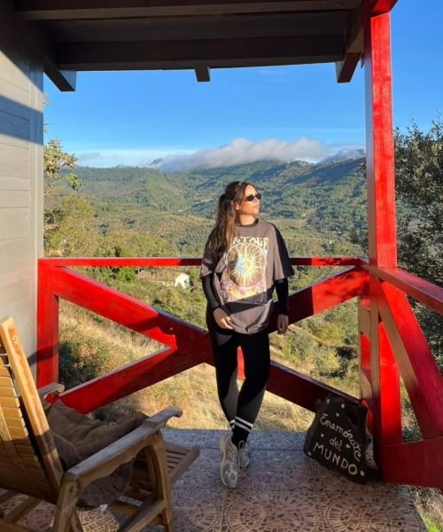 Veronica Villegas posando en la naturaleza con camiseta vintage, leggins y zapatillas deportivas.