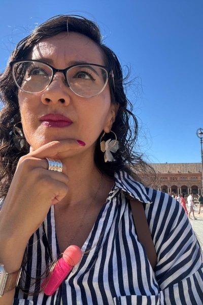María del Carmen Ramírez, creadora UGC, pensativa frente a la Plaza de España en Sevilla, disfrutando de la arquitectura.