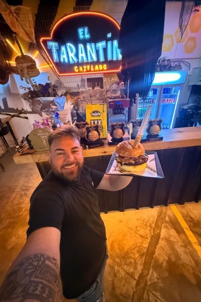 hombre mostrando hamburguesa grande en el tarantin restaurante ugc comida