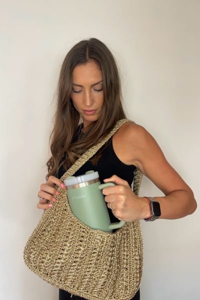 Creadora de contenido mostrando taza verde Natulim con bolsa de crochet