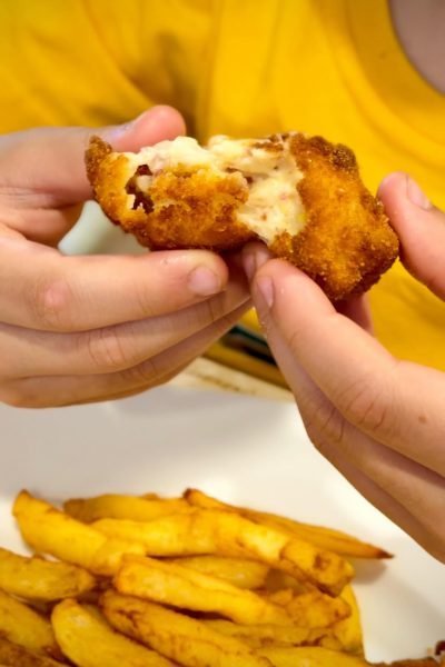 Croqueta abierta con relleno cremoso y patatas fritas, comida capturada por Ana Ayúcar, creadora de contenido foodie.