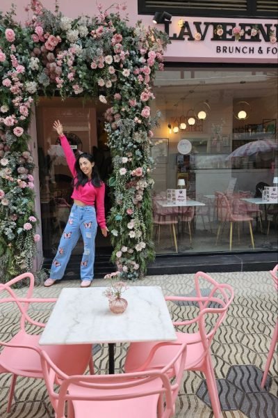 Ana Belén Valero posando frente a La Vie en Rose, disfrutando de un brunch en un local con decoración floral rosa.