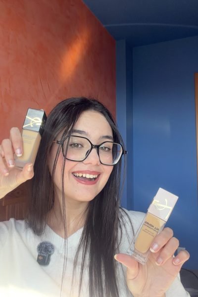 Andrea Suárez probando productos de maquillaje y mostrando las botellas frente a cámara.