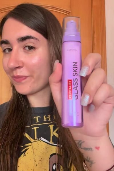 Esthela López mostrando el serum L’Oréal Revitalift Glass Skin frente a cámara, con piel luminosa y maquillaje natural.
