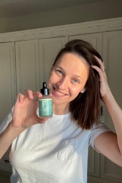 Alexandra Suciu, creadora UGC, mostrando un producto de cuidado capilar mientras sonríe genuinamente, destacando su estilo natural.