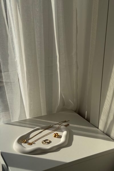 Conjunto de joyas doradas sobre una mesa blanca, con luz natural iluminando las piezas.